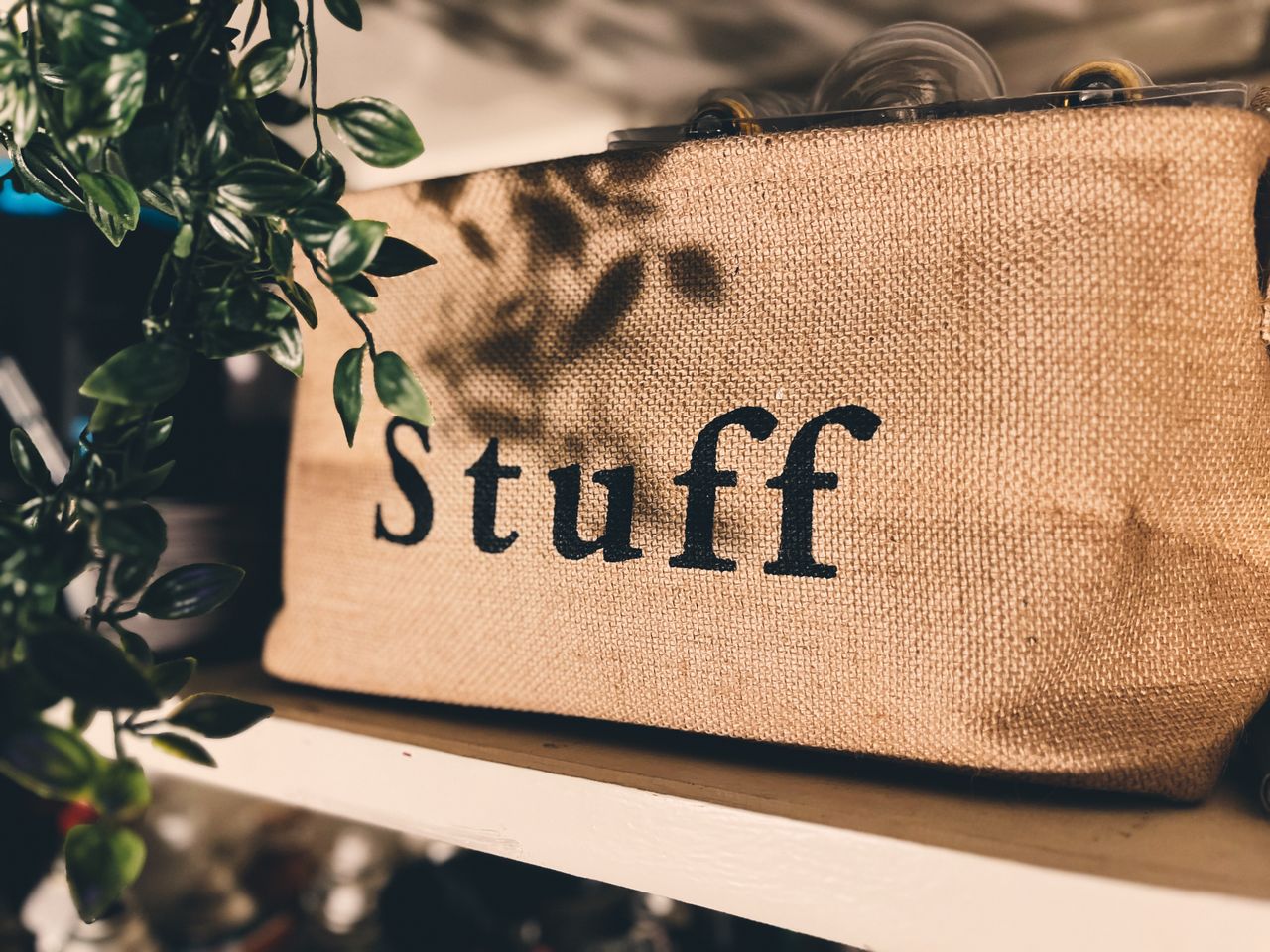 Close-up of a burlap bag labeled Stuff on a wooden shelf with plants.